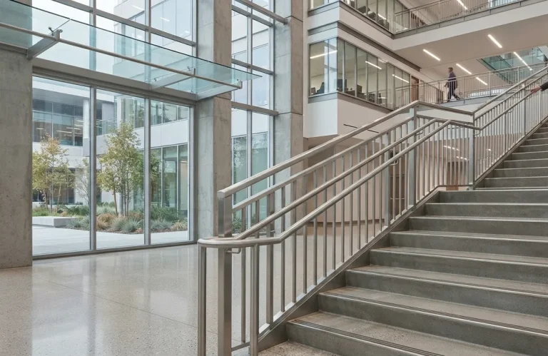 Stainless steel handrails beside an indoor staircase